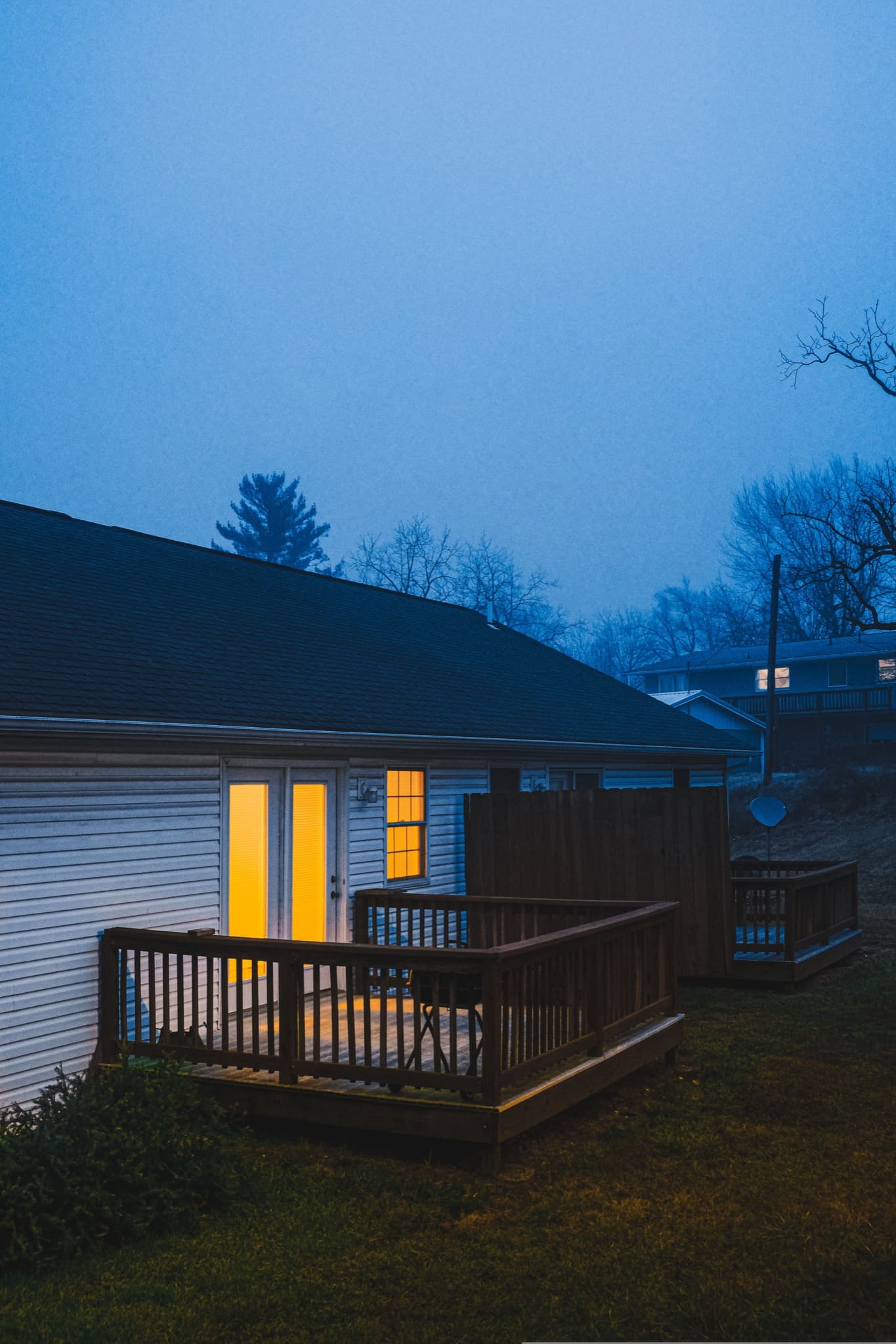 Rear deck and residential exterior illuminated during blue hour